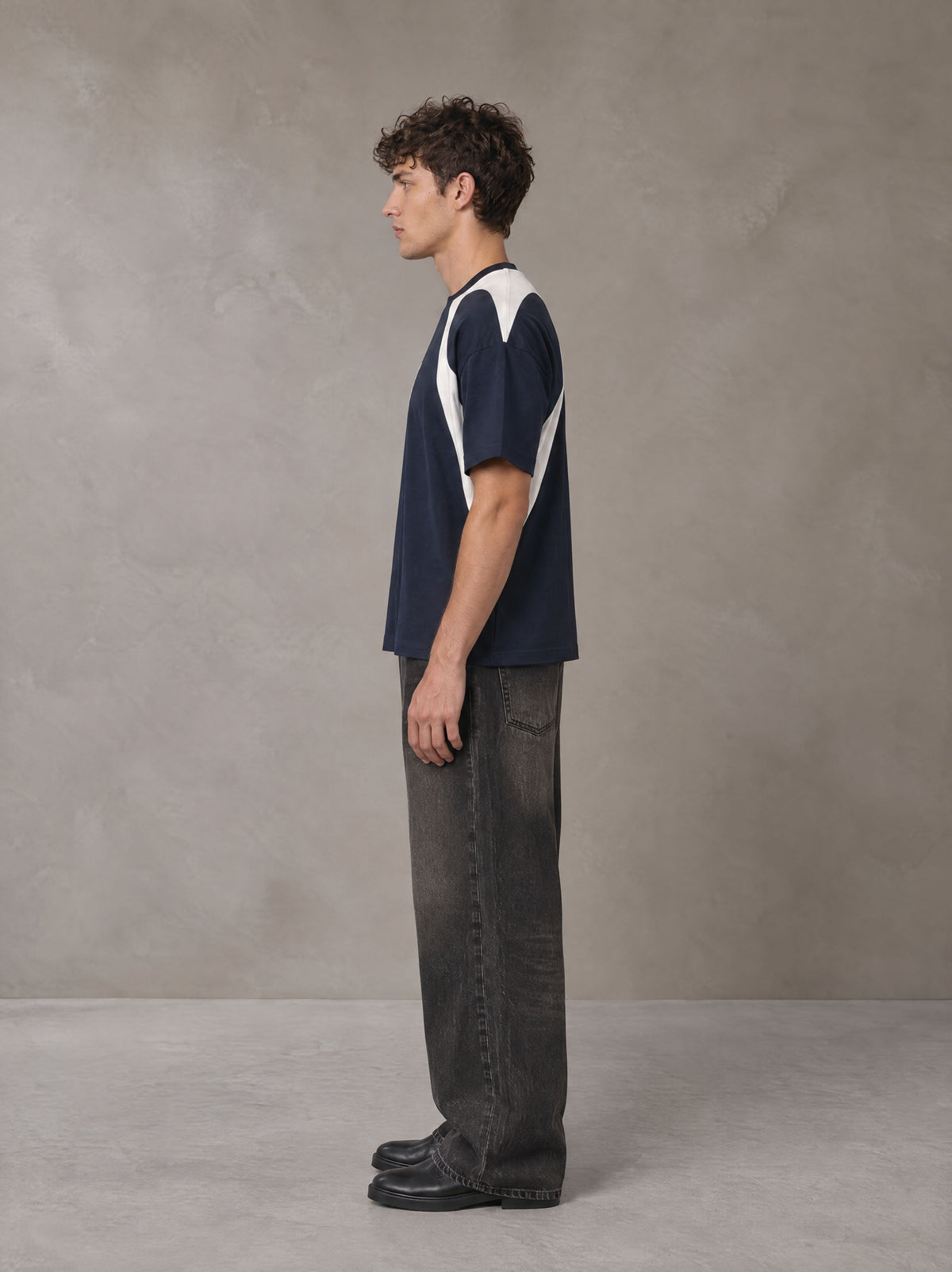 Model wearing the SM Graffiti Stack T-shirt in Oxford Navy, side profile.