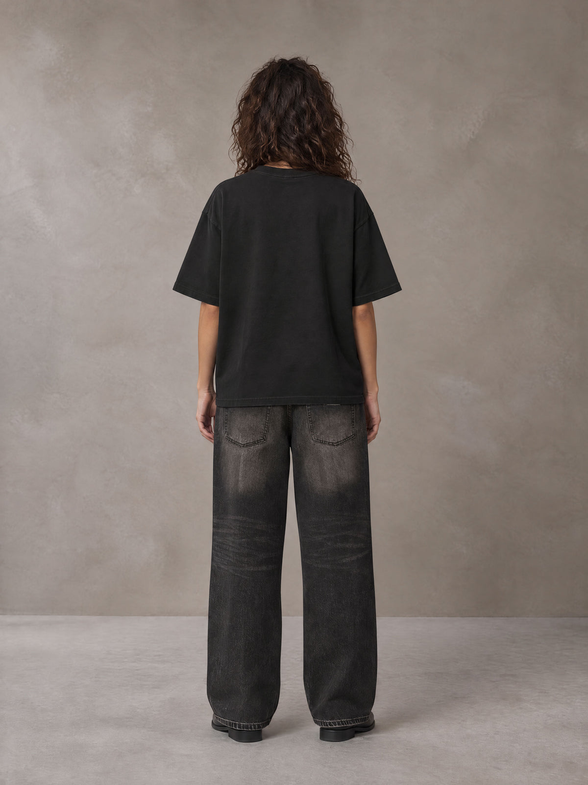 Model wearing the SM Halcyon T-shirt in Midnight Black, rear view.