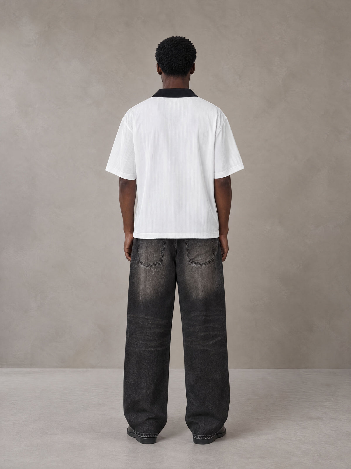 Model wearing the SM Legacy Jersey Polo T-shirt in Lucent White, rear view.