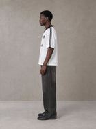 Model wearing the SM Legacy Jersey Polo T-shirt in Lucent White, side profile.