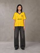 Model wearing the SM Legacy Jersey Polo T-shirt in Maize, front view.