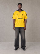 Model wearing the SM Legacy Jersey Polo T-shirt in Maize, front view.