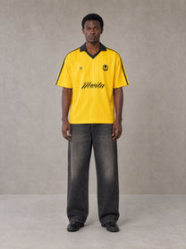 Model wearing the SM Legacy Jersey Polo T-shirt in Maize, front view.