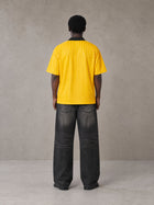 Model wearing the SM Legacy Jersey Polo T-shirt in Maize, rear view.