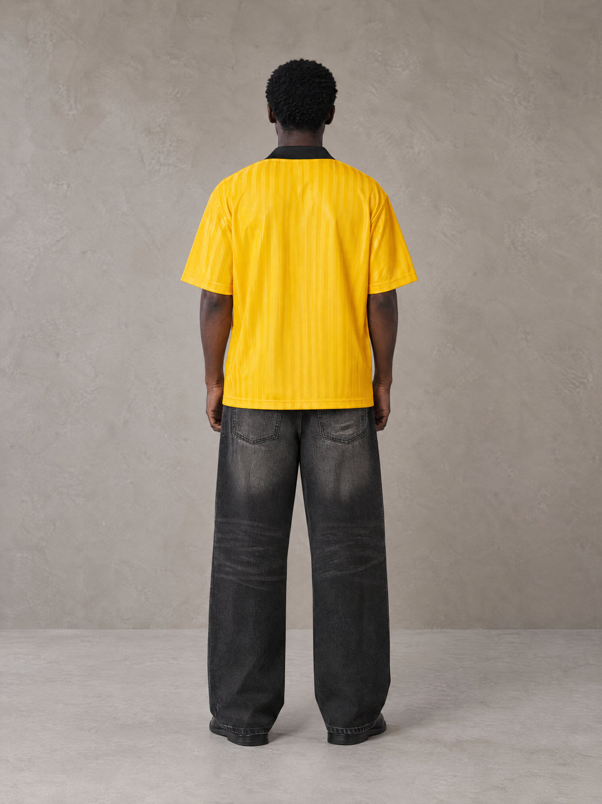 Model wearing the SM Legacy Jersey Polo T-shirt in Maize, rear view.
