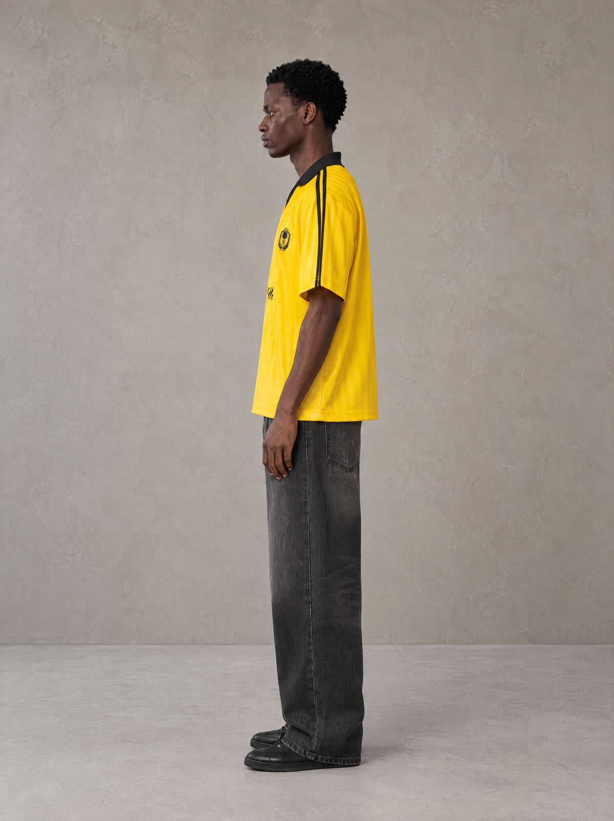Model wearing the SM Legacy Jersey Polo T-shirt in Maize, side profile.