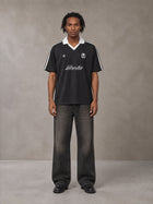 Model wearing the SM Legacy Jersey Polo T-shirt in Midnight Black, front view.