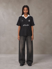 Model wearing the SM Legacy Jersey Polo T-shirt in Midnight Black, front view.