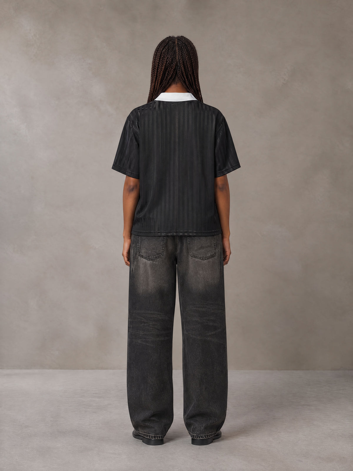 Model wearing the SM Legacy Jersey Polo T-shirt in Midnight Black, rear view.