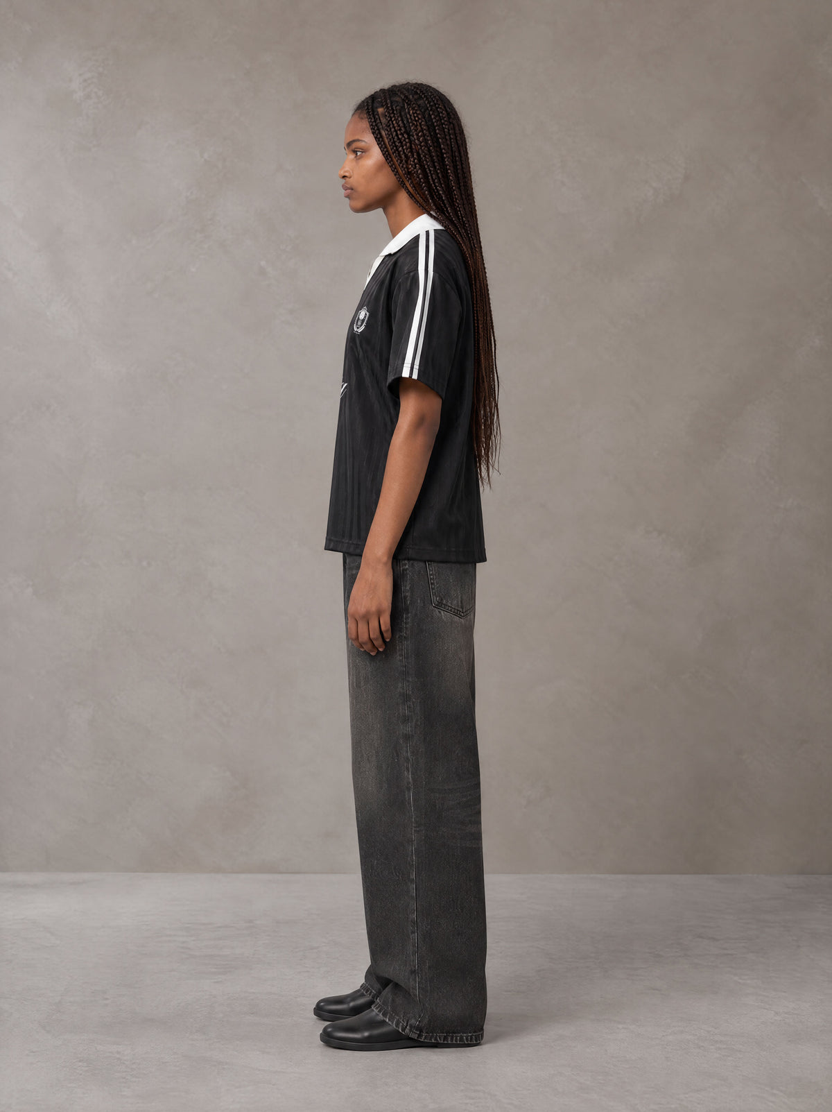 Model wearing the SM Legacy Jersey Polo T-shirt in Midnight Black, side profile.