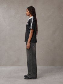 Model wearing the SM Legacy Jersey Polo T-shirt in Midnight Black, side profile.