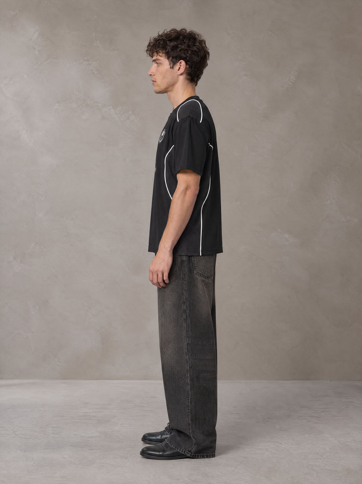 Model wearing the SM Legacy Jersey T-shirt in Midnight Black, side profile.