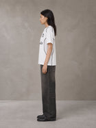 Model wearing the SM Legacy Jersey T-shirt in Lucent White, side profile.