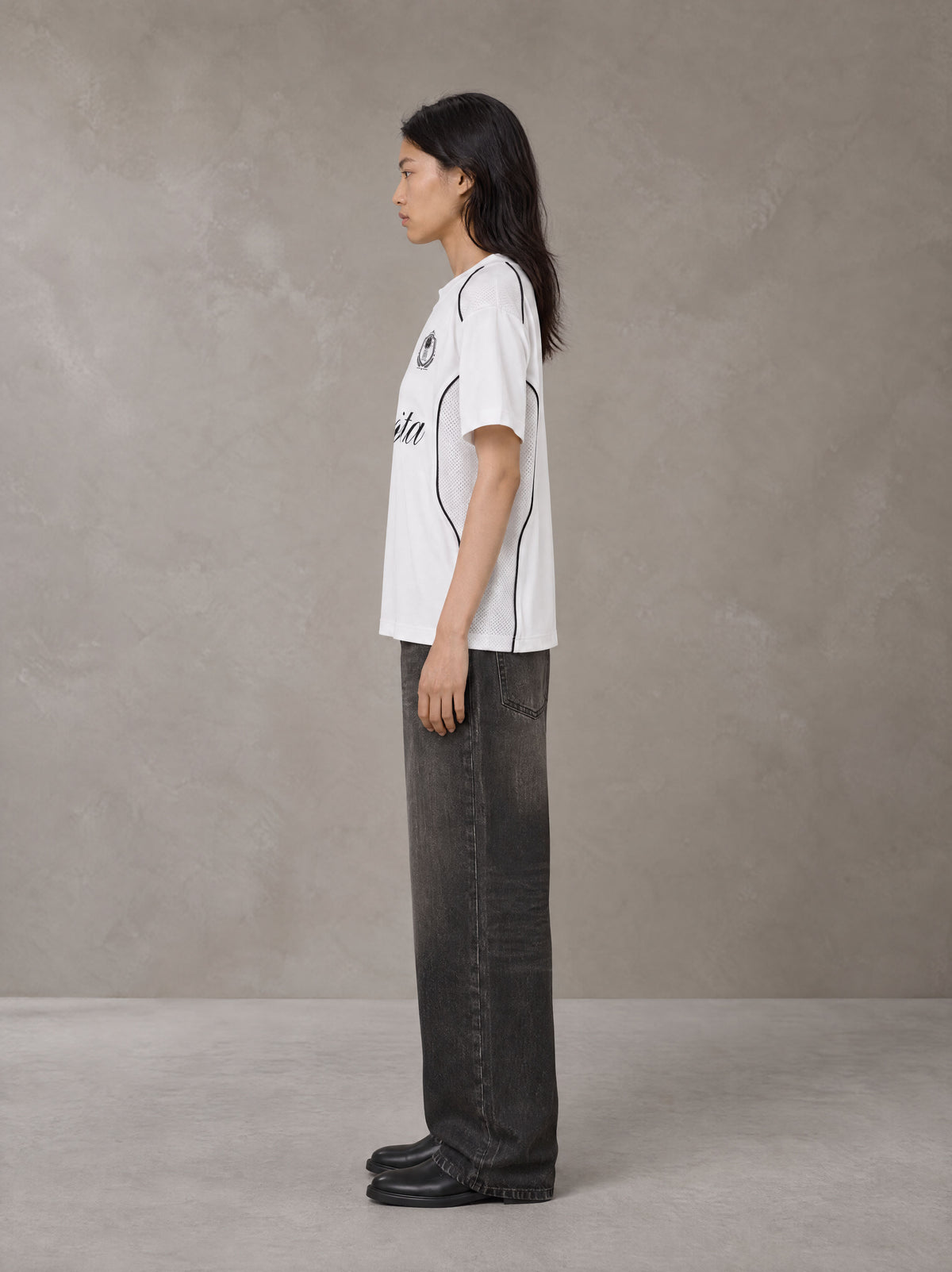 Model wearing the SM Legacy Jersey T-shirt in Lucent White, side profile.