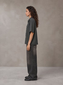 Model wearing the SM Pinstripe Short Sleeve Shirt in Deep Charcoal, side profile.