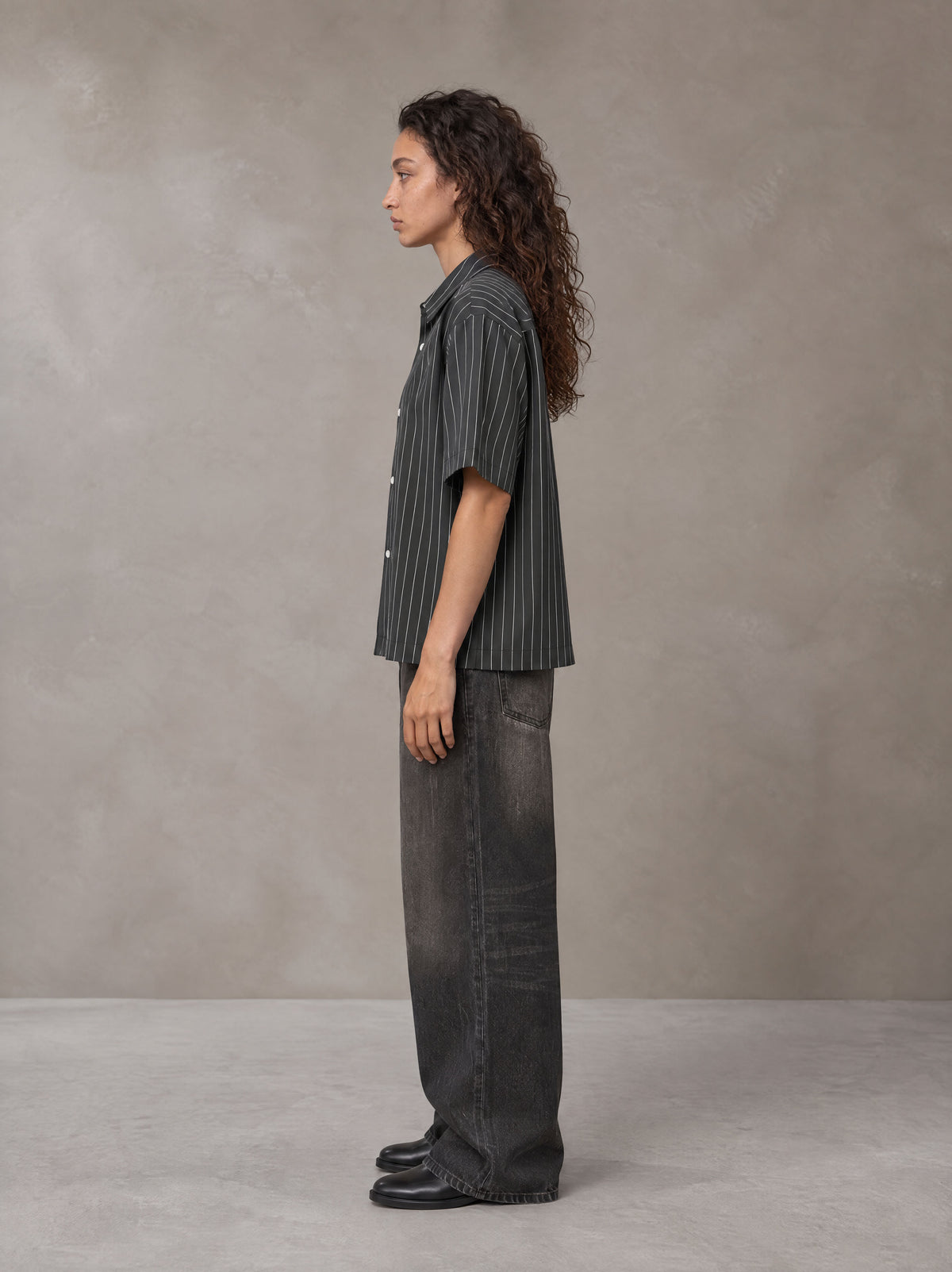 Model wearing the SM Pinstripe Short Sleeve Shirt in Deep Charcoal, side profile.