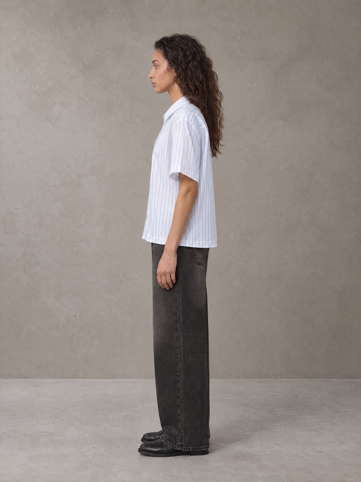 Model wearing the SM Pinstripe Short Sleeve Shirt in Lucent White, side profile.
