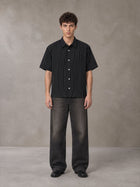 Model wearing the SM Pinstripe Short Sleeve Shirt in Midnight Black, front view.