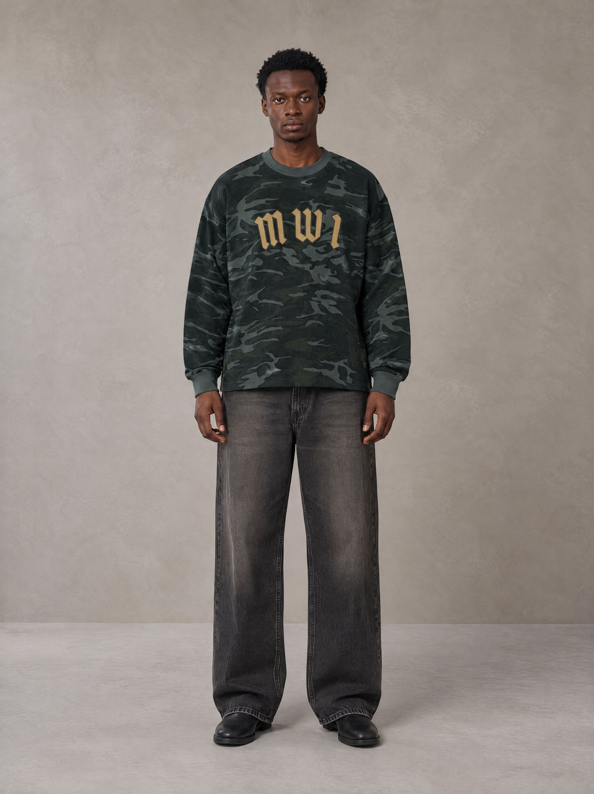 Model wearing the SM Script Camo Long Sleeve T-shirt in Jungle Green, front view.