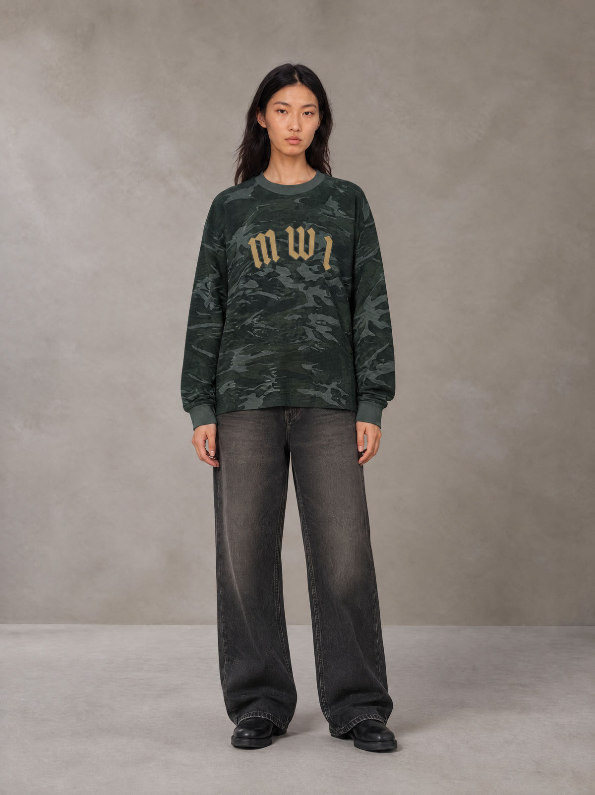 Model wearing the SM Script Camo Long Sleeve T-shirt in Jungle Green, front view.