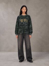 Model wearing the SM Script Camo Long Sleeve T-shirt in Jungle Green, front view.