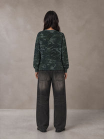 Model wearing the SM Script Camo Long Sleeve T-shirt in Jungle Green, rear view.