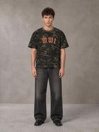 Model wearing the SM Script Camo T-shirt in Rangoon Green, front view.