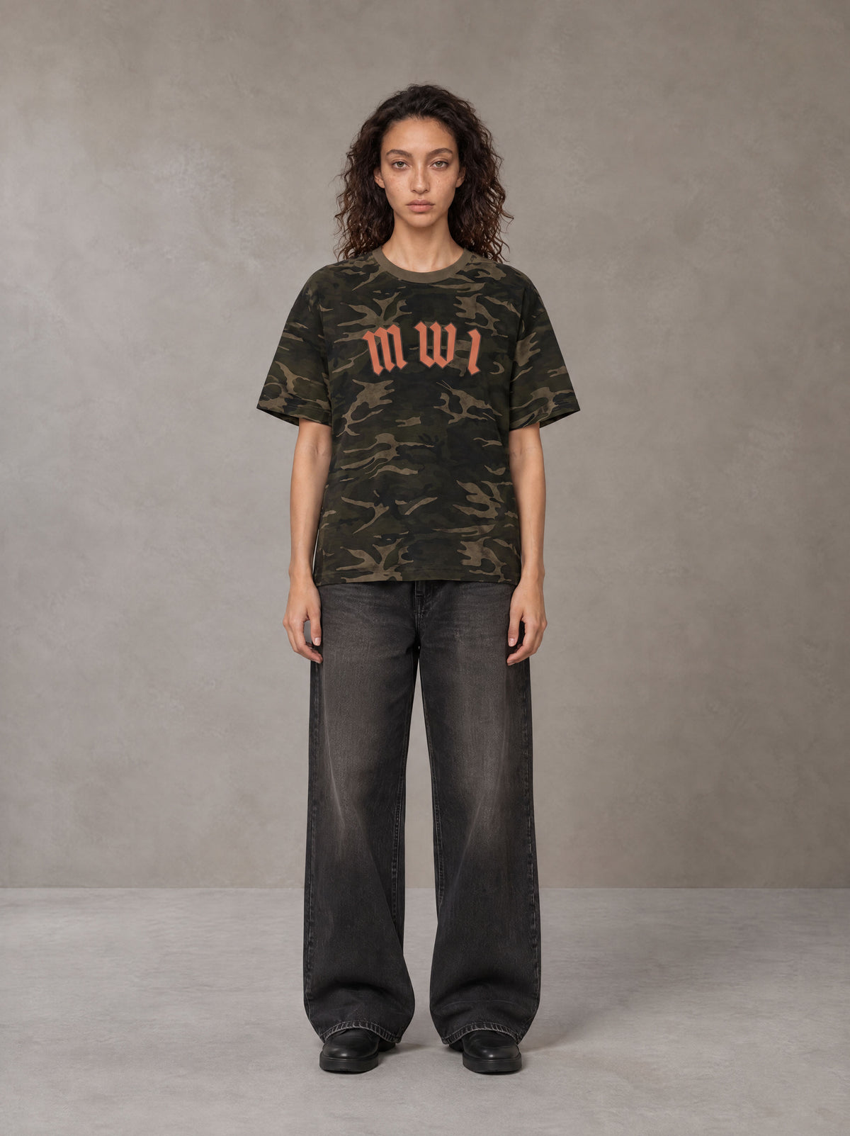 Model wearing the SM Script Camo T-shirt in Rangoon Green, front view.