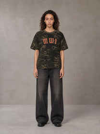 Model wearing the SM Script Camo T-shirt in Rangoon Green, front view.