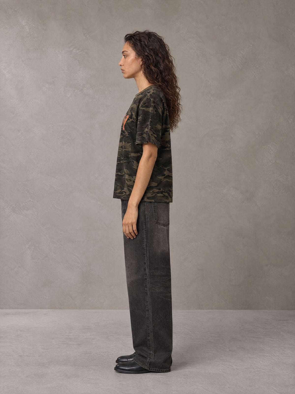 Model wearing the SM Script Camo T-shirt in Rangoon Green, side profile.