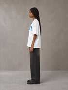 Model wearing the SM Script T-shirt in Lucent White, side profile.