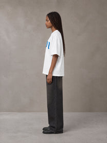 Model wearing the SM Script T-shirt in Lucent White, side profile.
