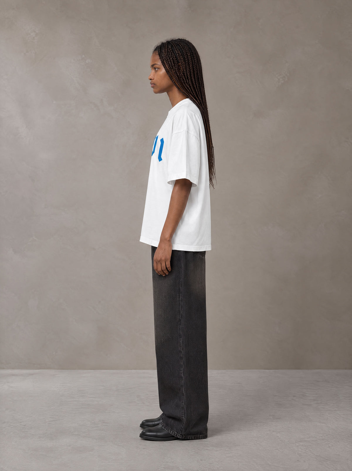 Model wearing the SM Script T-shirt in Lucent White, side profile.