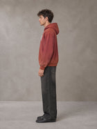 Model wearing the SM Script Washed Hoodie in Copper Rust, side profile.