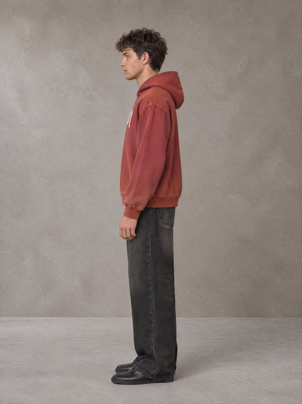 Model wearing the SM Script Washed Hoodie in Copper Rust, side profile.