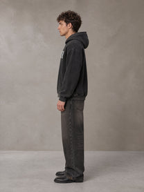 Model wearing the SM Script Washed Hoodie in Midnight Black, side profile.