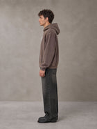 Model wearing the SM Script Washed Hoodie in Soft Taupe, side profile.