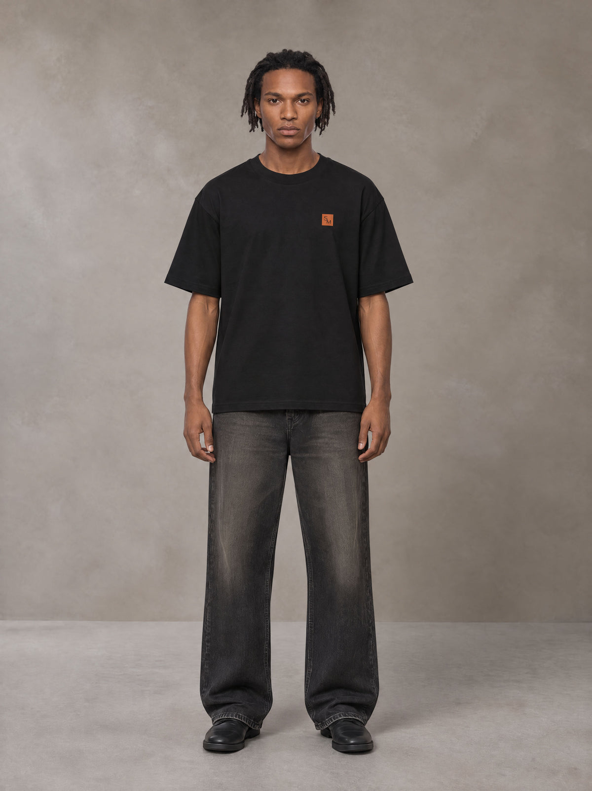 Model wearing the SM Sig. Oversized T-shirt in Midnight Black, front view.