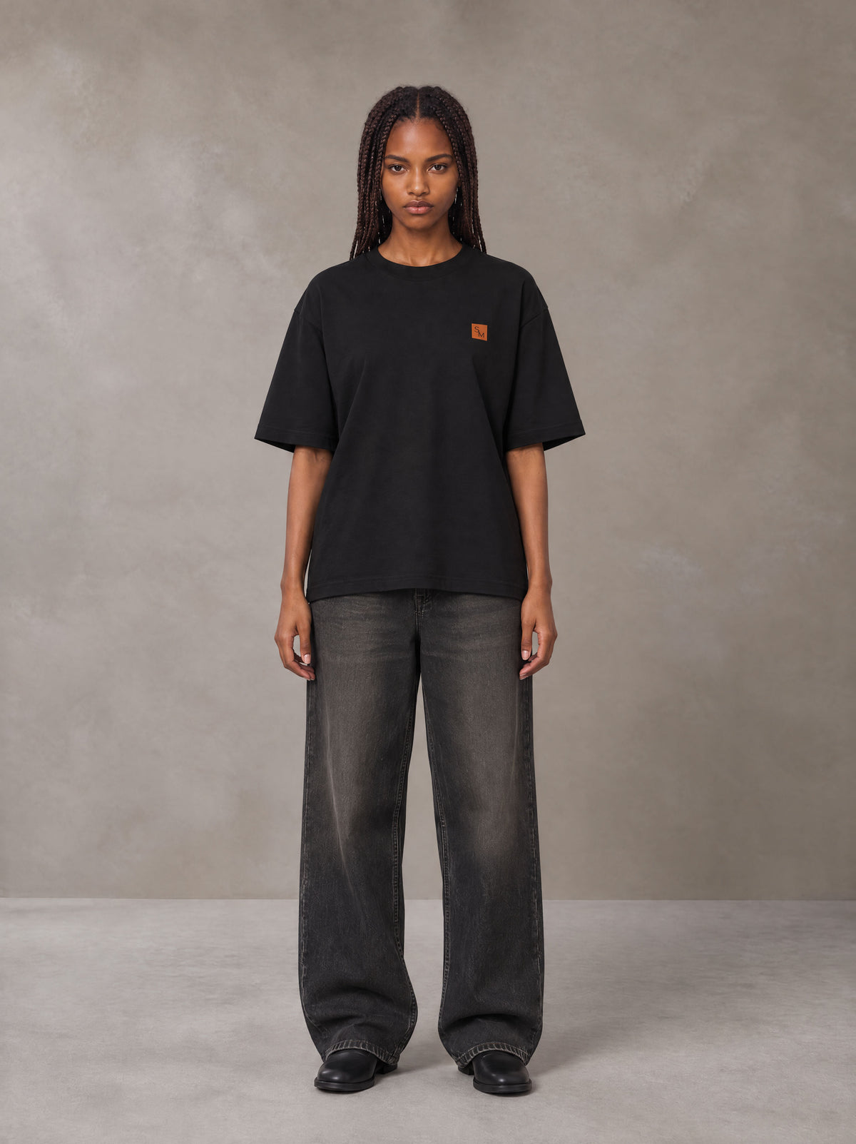 Model wearing the SM Sig. Oversized T-shirt in Midnight Black, front view.