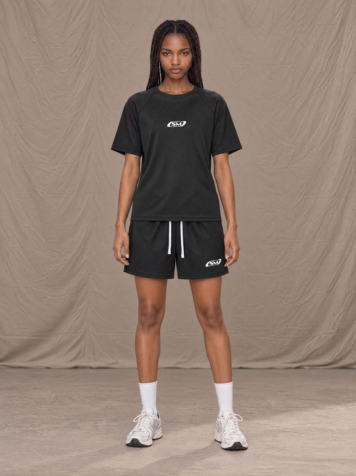 Model wearing the SM Motion Mesh T-shirt and SM Motion Mesh Shorts in black, front view.