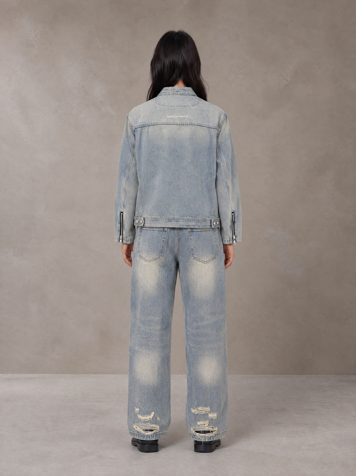 Model wearing the SM Vintage Wash Zip Denim Jacket and SM Heritage Distressed Denim Jeans in Cadet Grey, rear view.
