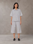 Model wearing the SM Distressed Plaid Boxy Shirt and SM Plaid Capri Shorts in Lucent White, front view.
