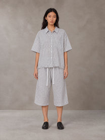 Model wearing the SM Distressed Plaid Boxy Shirt and SM Plaid Capri Shorts in Lucent White, front view.