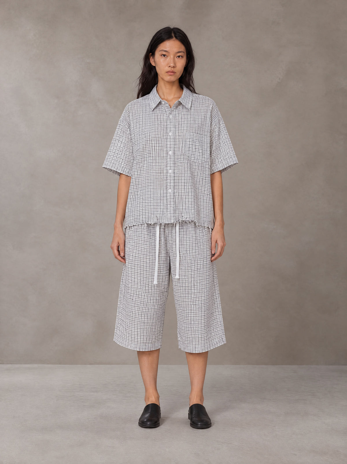 Model wearing the SM Distressed Plaid Boxy Shirt and SM Plaid Capri Shorts in Lucent White, front view.