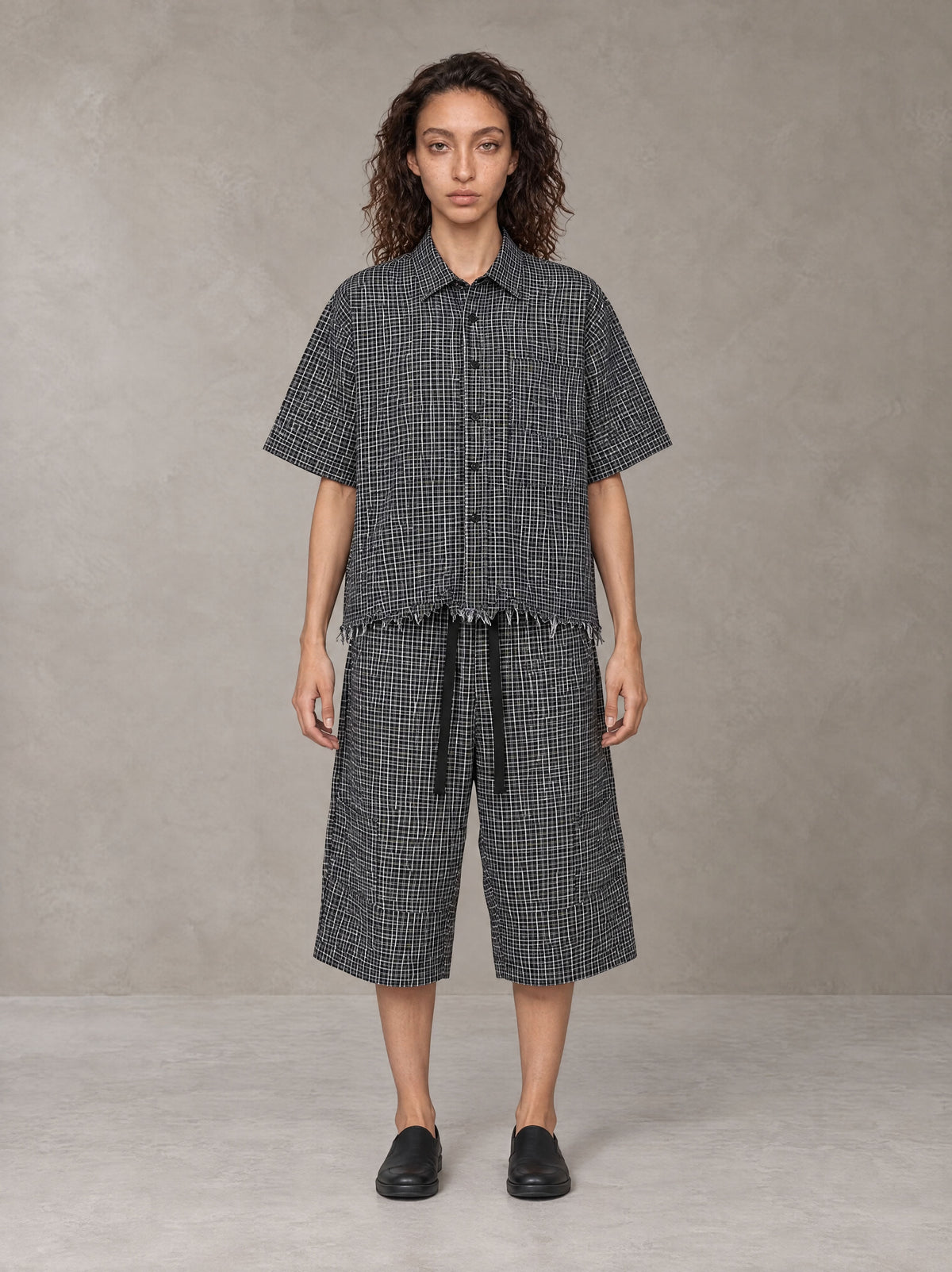 Model wearing the SM Distressed Plaid Boxy Shirt and SM Plaid Capri Shorts in Midnight Black, front view.