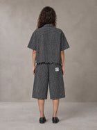 Model wearing the SM Distressed Plaid Boxy Shirt and SM Plaid Capri Shorts in Midnight Black, rear view.