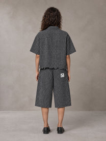 Model wearing the SM Distressed Plaid Boxy Shirt and SM Plaid Capri Shorts in Midnight Black, rear view.