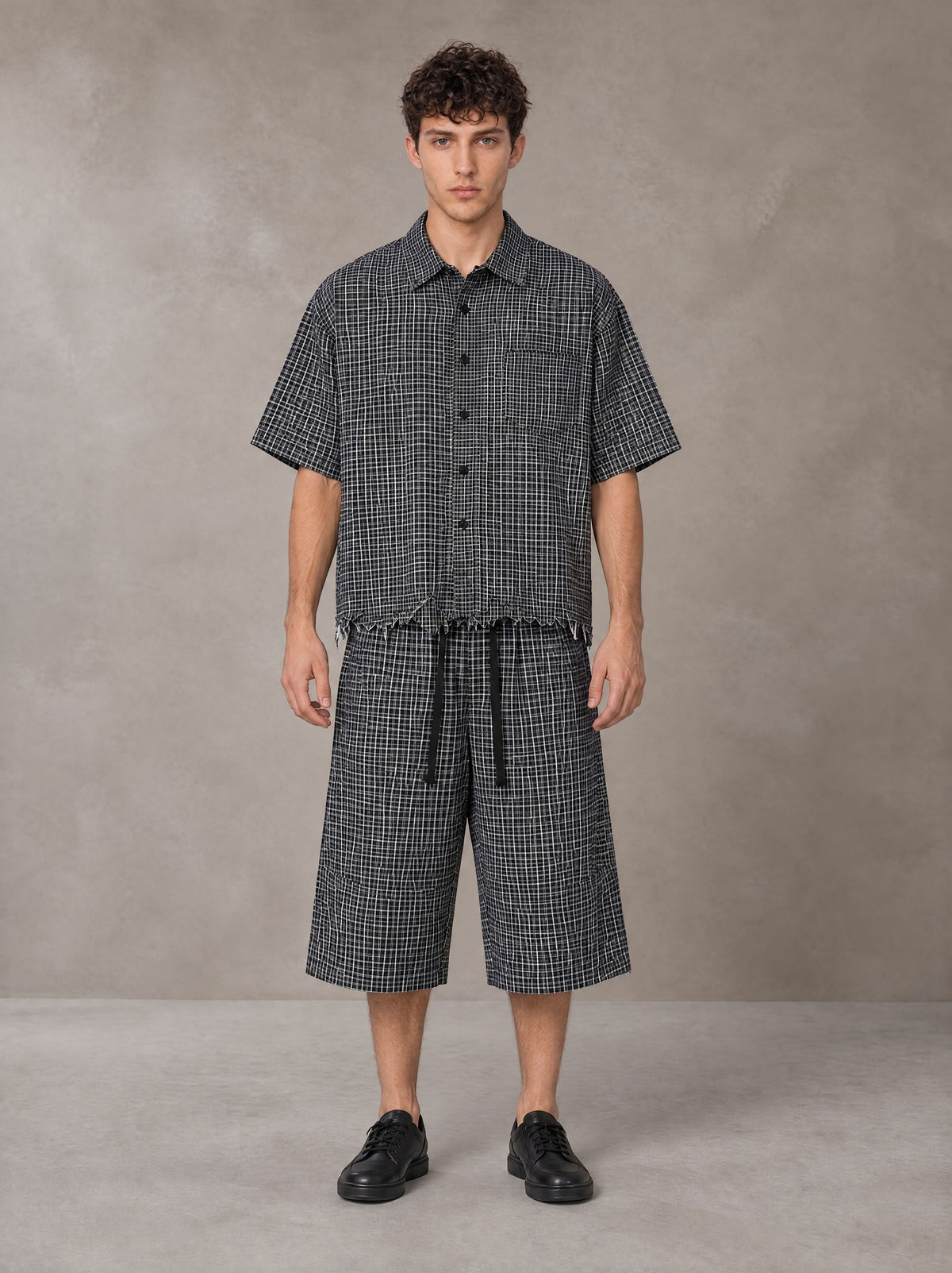 Model wearing the SM Distressed Plaid Boxy Shirt and SM Plaid Capri Shorts in Midnight Black, front view.