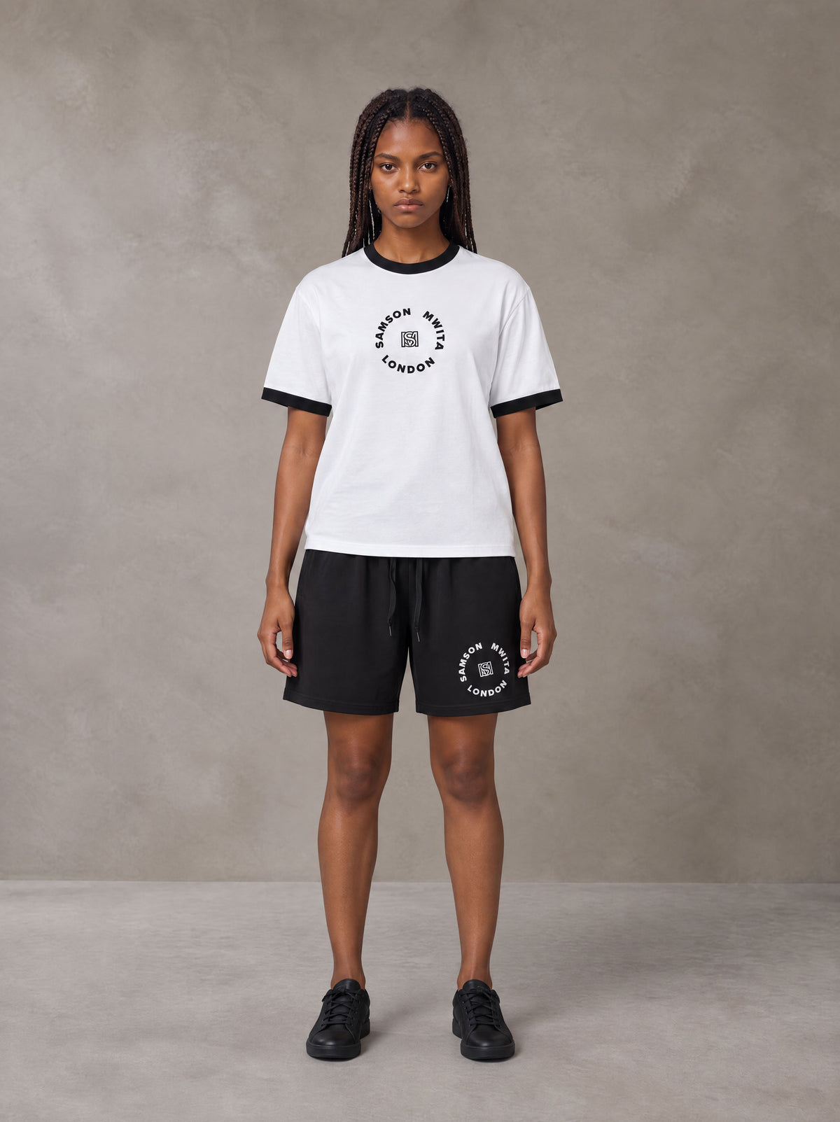Model wearing the SM London T-shirt in Lucent White with the SM London Shorts in Midnight Black, front view.